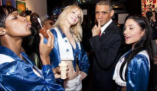 A group of people at a social event, with two women wearing shiny blue and white satin jackets and a man in a black suit standing in the center.